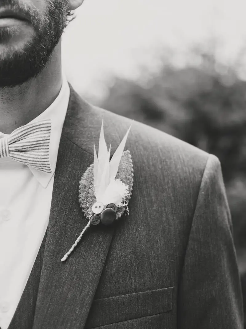 Traje gris con corbatín y flor en la solapa